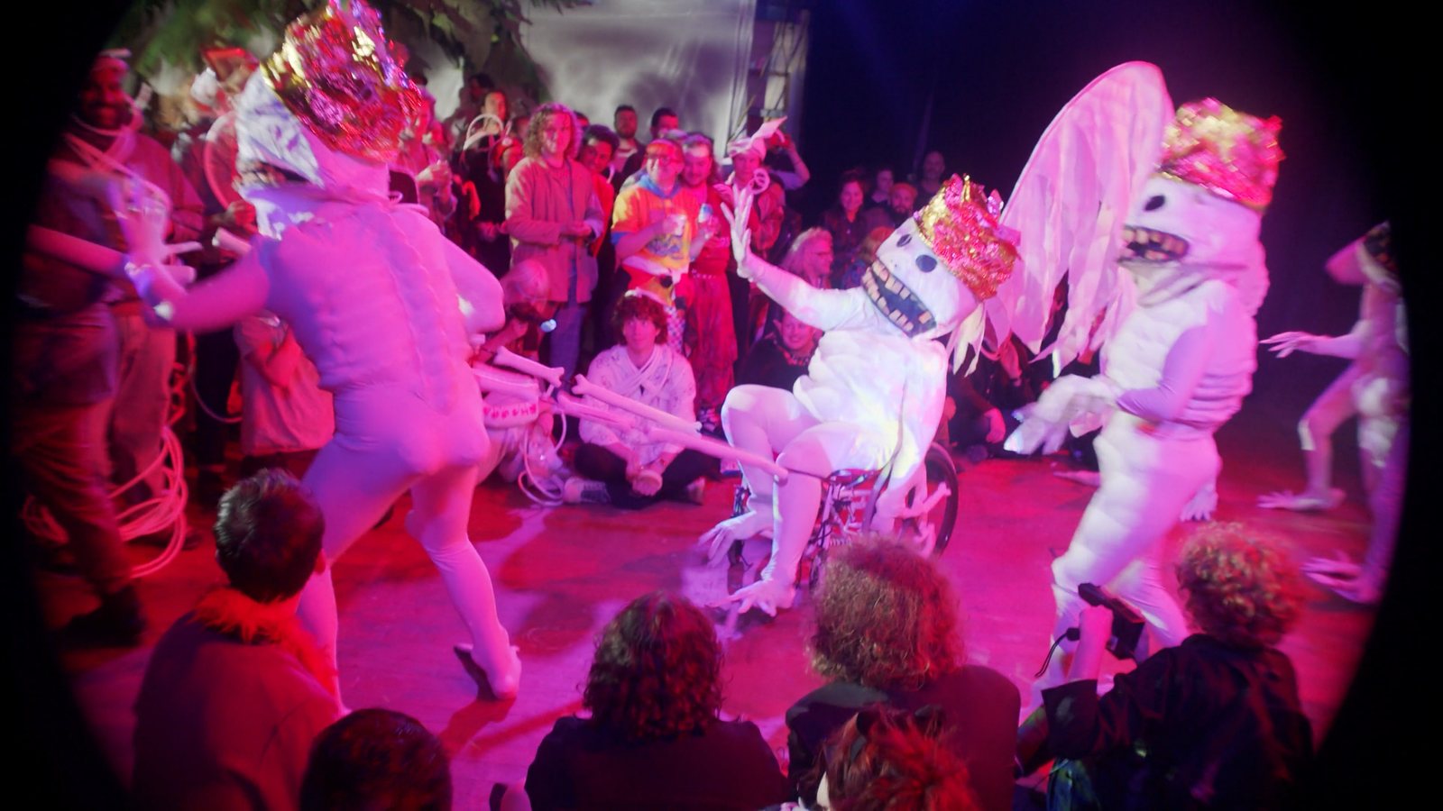 Costumed performers on stage under pink light