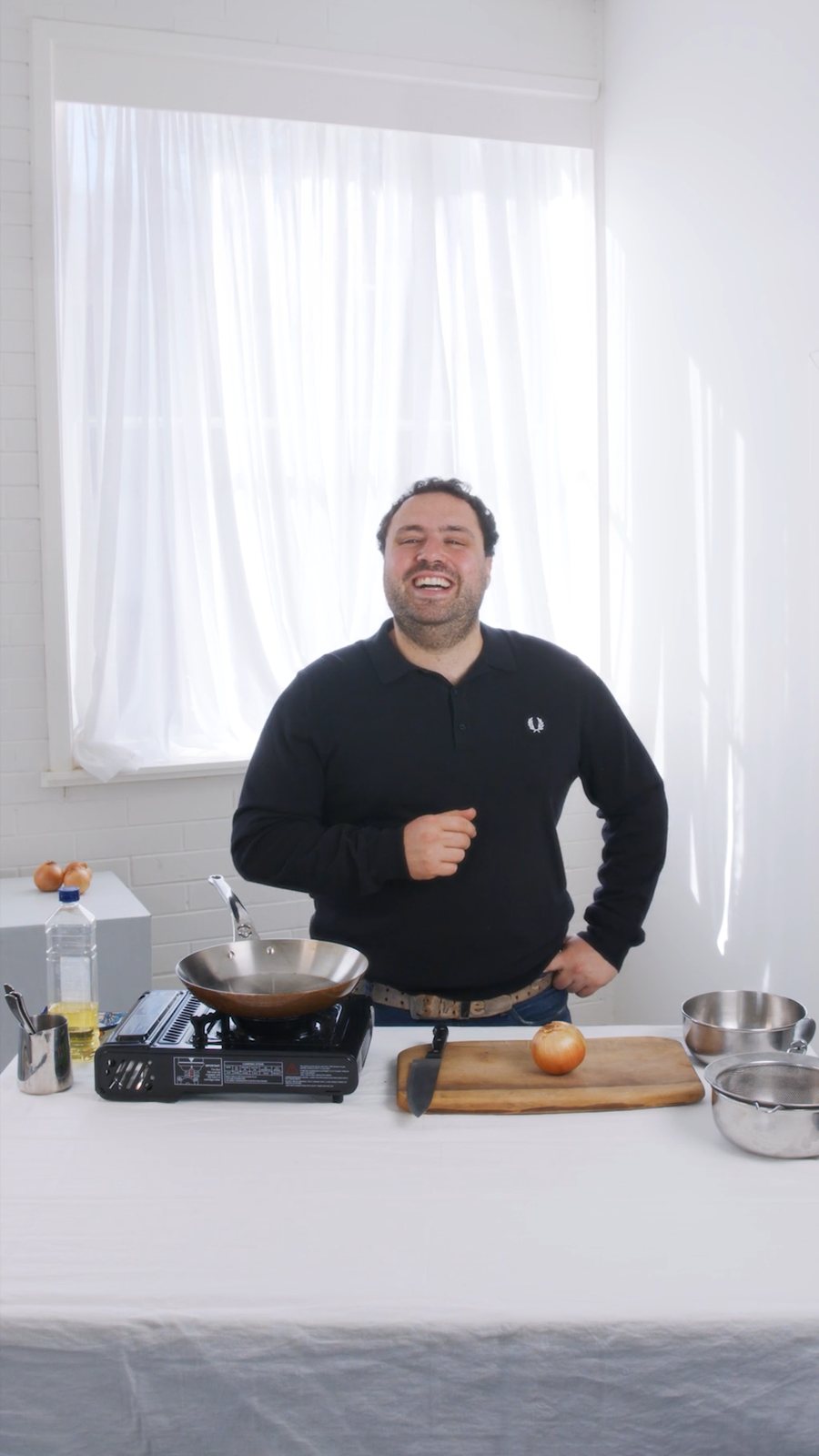 Presenter at a cooking bench in the studio, white curtained backdrop
