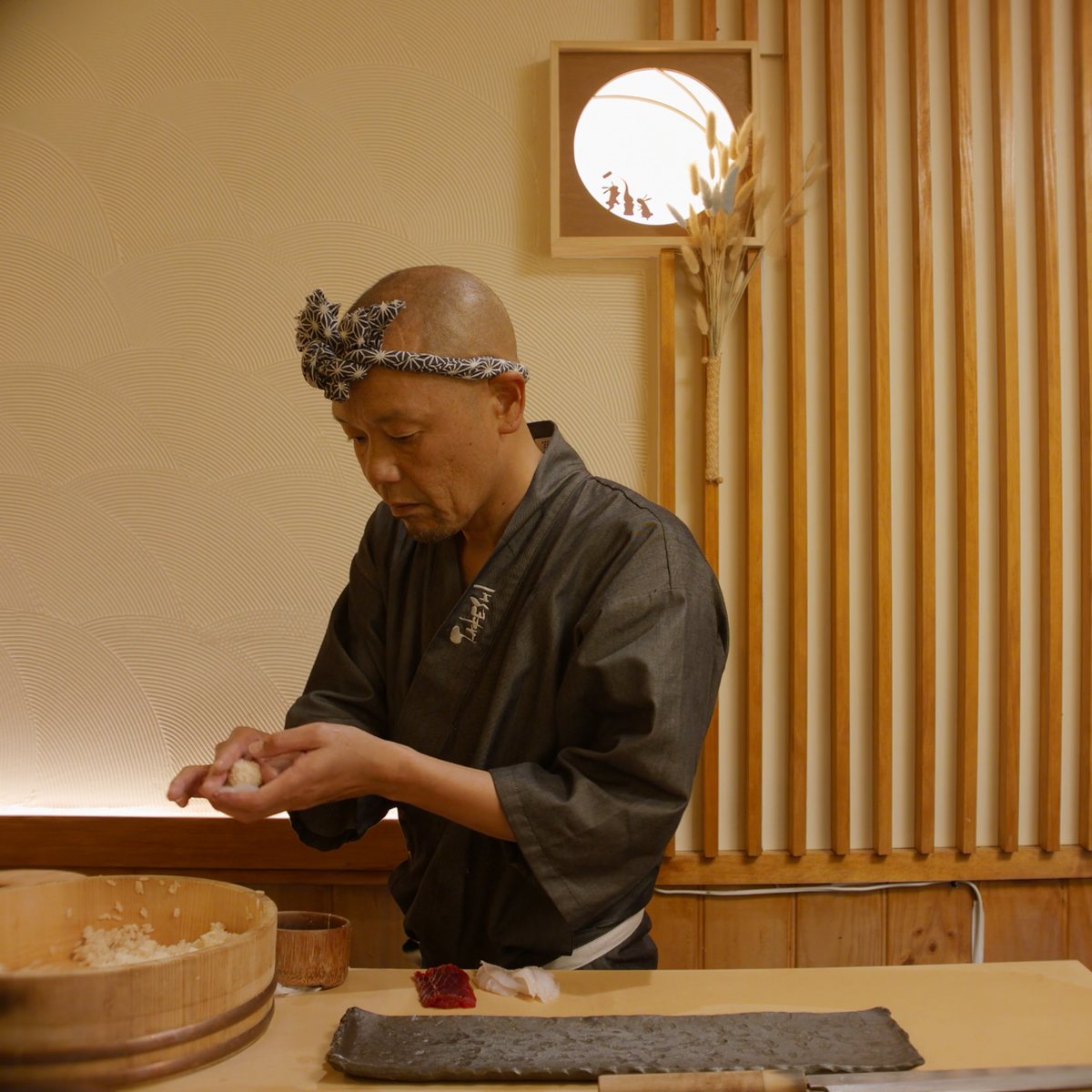 Sushi chef at work in a timber-lined room